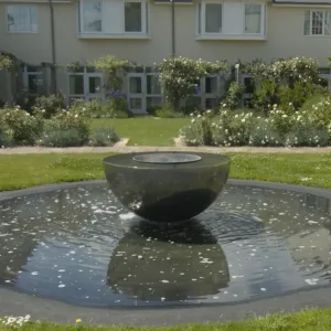 A circular fountain with a central bowl sculpture in the Penny Brohn garden