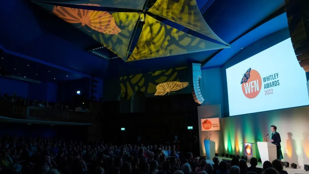 A wide shot of the auditorium stage at the Whitley Awards 2022 at the RGS in London, featuring Princess Anne at the podium, used for live stream production coverage.