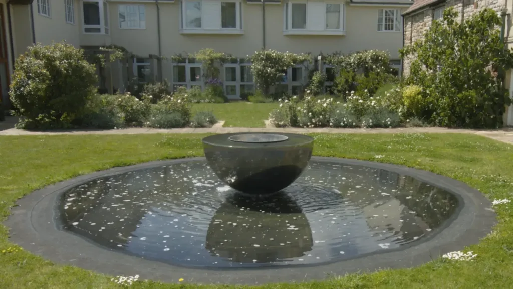 A circular fountain with a central bowl sculpture in the Penny Brohn garden
