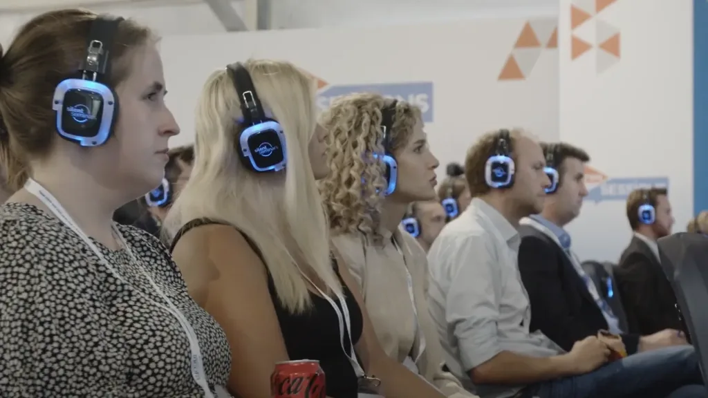 Audience wearing illuminated silent-event headphones during a ZeroAvia presentation at Farnborough International, filmed by Floating Harbour.