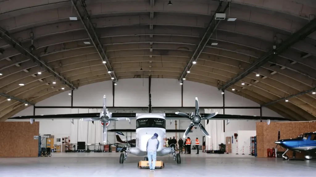 Wide front view of a ZeroAvia aircraft inside a large hangar with crew standing nearby
