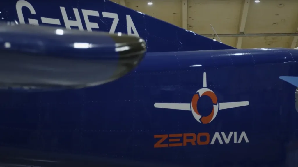 Close up of the ZeroAvia logo and tail section of a blue aircraft in a hangar
