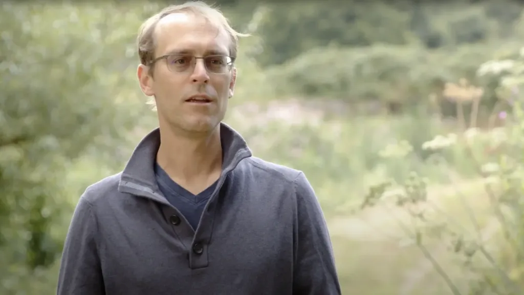 Matt Eggers speaks during an outdoor interview with greenery in the background