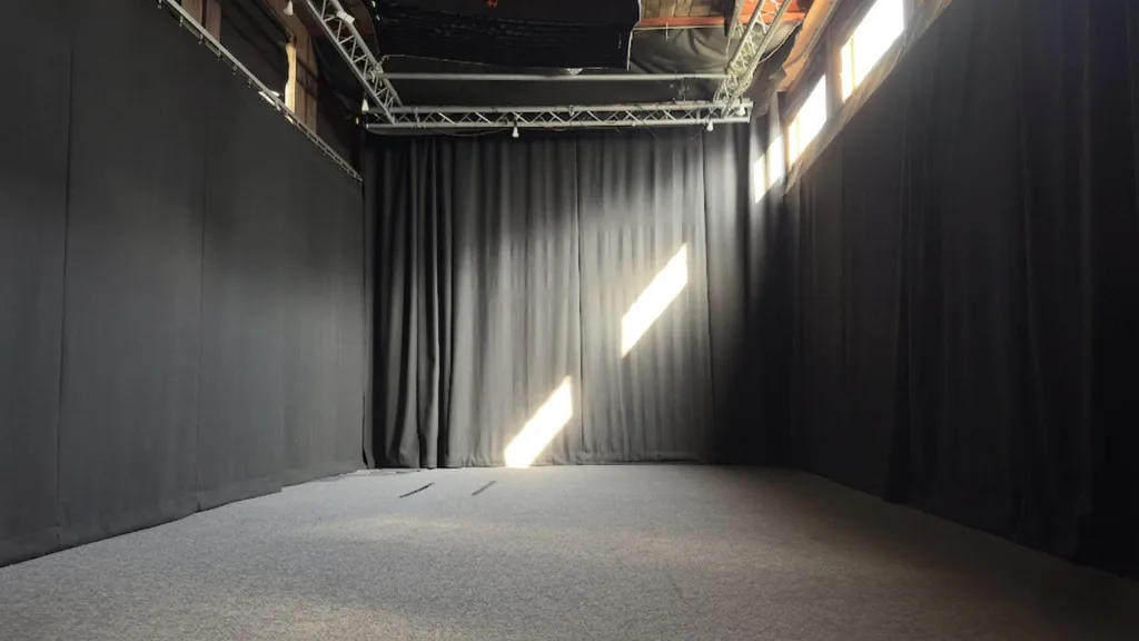 Interior of The Hold Studio at Floating Harbour Bristol – a black box film studio with full-height dark drapes, carpeted floor, lighting rig and truss, available to hire for film shoots, music videos and commercial productions