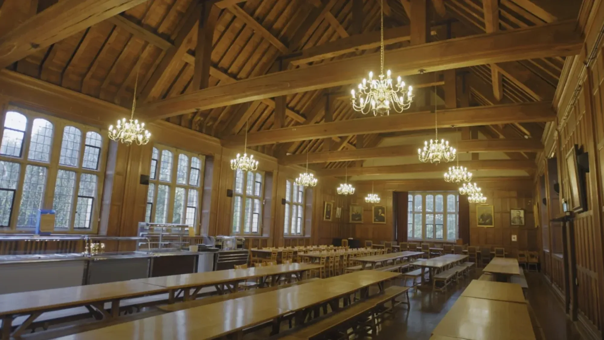 Wood-panelled dining hall with chandeliers and long tables at the University of Bristol.
