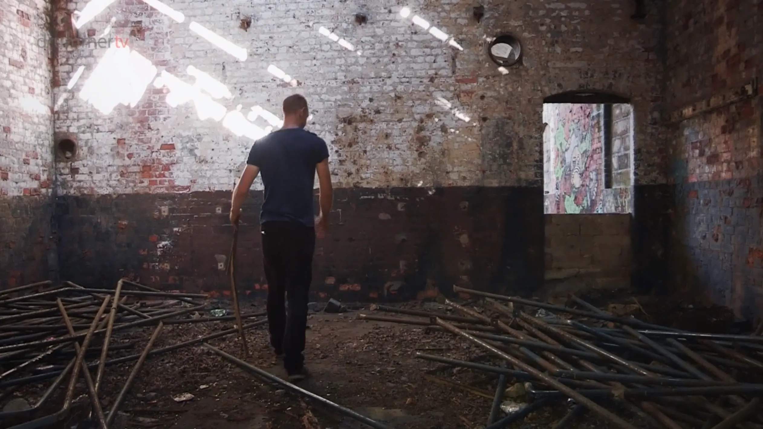 A man walks through a derelict brick building filled with scattered metal poles, filmed by Floating Harbour for the BBC Drama TV series Where Are You Sleeping Tonight.
