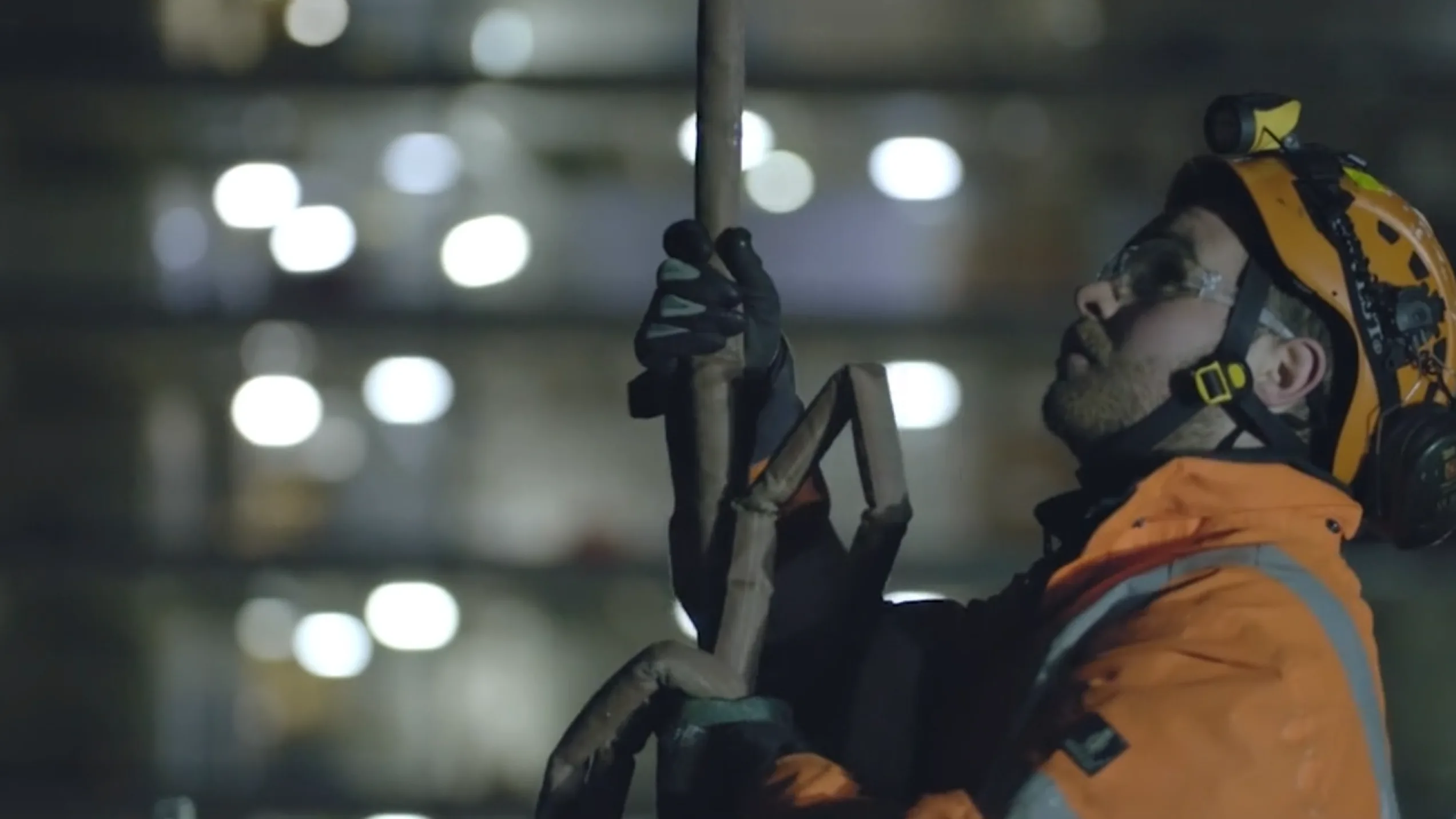 A steelworker in safety gear operating equipment at night on a Severfield construction project in London, filmed by Floating Harbour for a safety and training video.