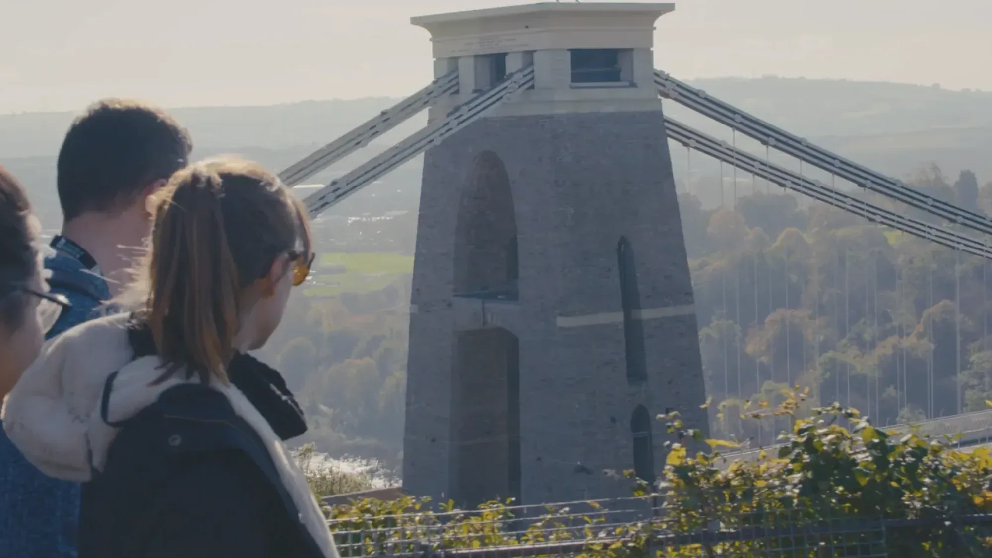 Group of students look towards the Clifton Suspension Bridge tower in bright daylight